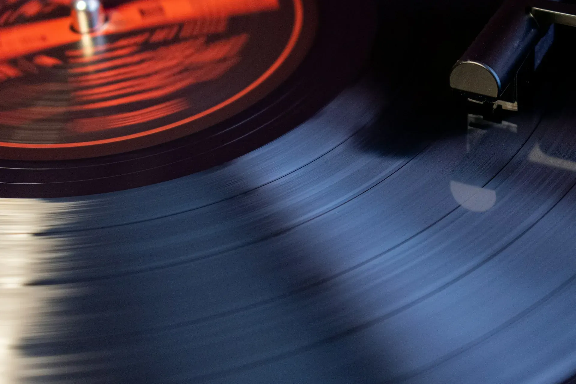 A vinyl record spinning on a turntable, its orange label blurred by motion